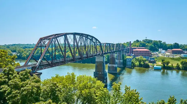 Nashville, Tennessee 'deki tarihi kırmızı tuğla binaların yakınlarındaki yemyeşil manzaraları birbirine bağlayan paslı bir nehir üzerindeki demiryolu köprüsünün havadan görüntüsü. Endüstriyel miras temaları için mükemmel.