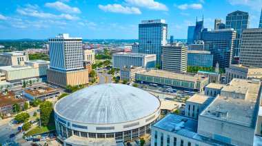 Vibrant aerial view of downtown Nashville featuring the iconic Bridgestone Arena and bustling streets. The skyline blends modern and classic architecture under a clear blue sky. Perfect for urban and clipart