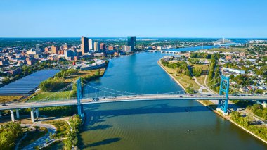 Toledo Ohio 'nun hava görüntüsü Maumee Nehri' ni kaplayan ikonik Anthony Wayne Köprüsü 'nü gösteriyor. Canlı şehir manzarası modern gökdelenleri, açık mavi gökyüzü altında tarihi bir cazibeyle harmanlıyor..