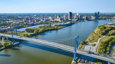 Toledo ikonik Anthony Wayne Köprüsü 'nün Maumee Nehri' ni kaplayan hava görüntüsü. Canlı bir şehir hayatı, yemyeşil bir yer ve güneşli Ohio gökyüzünün altında dinamik bir ufuk çizgisi. Şehir planlaması için mükemmel.