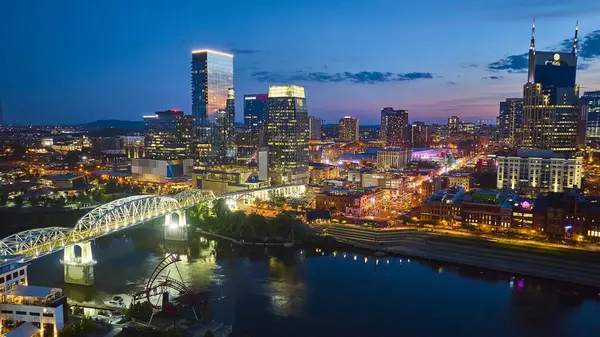 stock image Nashville skyline sparkles during the blue hour as the John Seigenthale Pedestrian Bridge stretches over the calm Cumberland River, connecting vibrant downtown with its lively nightlife.