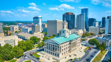 Nashville şehir merkezinin dinamik hava manzarası modern gökdelenlerin ortasındaki ikonik Tennessee Eyalet Kongre Binası 'nı gösteriyor, açık mavi gökyüzü altında tarihin ve büyümenin canlı bir karışımını yansıtıyor..