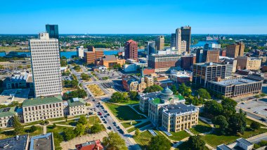 Aerial view of Toledo Ohios downtown skyline. The golden-domed Lucas County Probate Court stands among modern towers and lush green spaces, showcasing a blend of history and urban growth. clipart