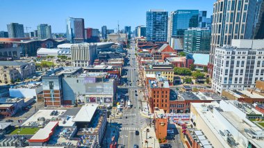 Bridgestone Arena ve Broadway Caddesi 'nin altın saatinde Nashville şehir merkezinin canlı görüntüsü. Dinamik şehir manzarası modern mimariyle canlı şehir yaşamını harmanlıyor..