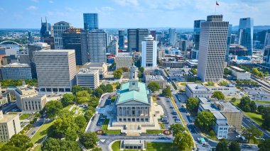 Nashville 'in hava manzarası canlı şehir merkezi siluetinin ortasındaki Tennessee Eyalet Kongre Binası' nı gösteriyor. Neoklasik mimari, açık mavi gökdelenler altında modern gökdelenlerle harmanlanır..