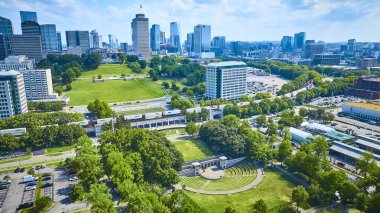 Vibrant aerial view of Nashville skyline with modern and classical architecture, lush Bicentennial Capitol Mall State Park, and bustling transit lines under a clear sky, showcasing urban life. clipart