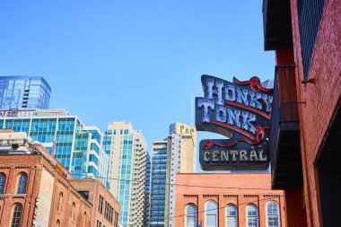 Nashville şehir merkezinin canlı şehir manzarasında ikonik Honky Tonk Central işareti var. Modern gökdelenler ve tarihi binaların bir karışımı Broadway Caddesi 'ndeki şehirlerin canlı müzik kültürünü yansıtıyor..