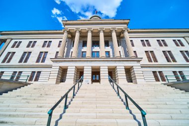 Majestic view of the Tennessee State Capitol in Nashville. The neoclassical facade with grand columns and a wide staircase under clear blue skies exudes authority and historical grandeur. clipart