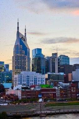 Günbatımında Nashville silueti modern ve tarihi mimarinin bir karışımı arasında ikonik Batman Binası 'nı sergiliyor. Şehrin ışıkları parıldarken kuşlar havada süzülür, şehrin canlı ruhunu ve cazibesini yakalar.