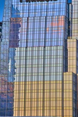 Güneşin altın rengi bir Nashville gökdeleninin cam cephesini aydınlatır. Canlı şehir manzarasını yansıtan bu şehir harikası modern mimariyi ve kurumsal zarafeti simgeliyor..