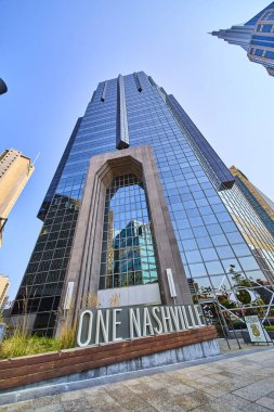 Bir Nashville gökdeleni Nashville, Tennessee şehir merkezinde parlak cam cephesini ve modern tasarımını sergileyerek açık mavi gökyüzüne yükselir. Kentsel gelişim ve kurumsal imajlar için mükemmel.