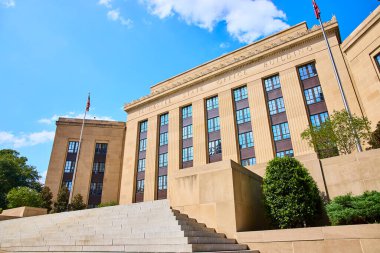 Nashville 'deki Majestic Tennessee Eyalet Binası açık mavi gökyüzünün altında parlıyor. Klasik mimarisi ve Amerikan bayrağı, yemyeşil ortamda yönetim ve sivil gururu çağrıştırıyor.