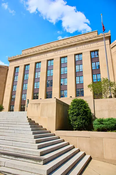Nashville 'deki Tennessee Eyalet Binası' nın görkemli manzarası. Klasik mimari, yüksek sütunlar, dalgalı bir bayrak ve mavi gökyüzü tarafından vurgulanan devlet gururu ve yönetimini somutlaştırır..