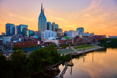 Altın saat Nashville ikonik siluetini sıcak bir ışıltıyla yıkar. Batman Binası, Cumberland Nehri 'nde yansıtılan modern ve tarihi mimarinin tam ortasında duruyor ve sakin bir şehir manzarası yaratıyor..