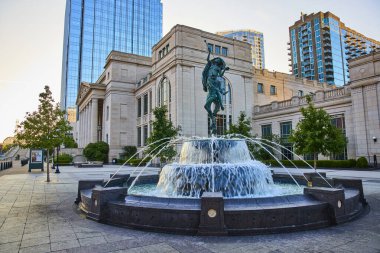 Klasik bronz heykelli görkemli çeşme Nashville 'deki Schermerhorn Senfoni Merkezi' ndeki şehir meydanını şereflendiriyor. Altın saat ışığı, tarihi mimari ve modern gökdelenlerin karışımını geliştiriyor..