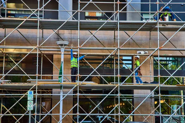 stock image Construction workers on scaffolding in Nashville city are busy at work. Wearing safety gear, they demonstrate teamwork and industry, highlighting the essence of urban development and safety protocols.