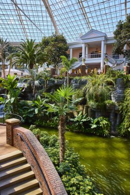 Explore tranquility at Gaylord Opryland in Nashville. This lush indoor garden features vibrant tropical plants, a serene waterfall, and elegant architecture, perfect for a luxury escape.