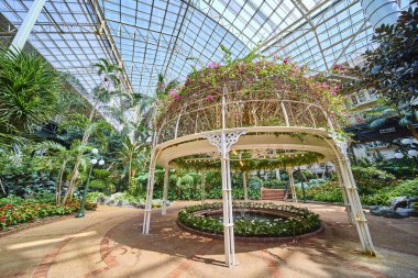 Explore tranquility at Gaylord Opryland indoor oasis in Nashville. A lush garden with an ornate gazebo and water feature invites relaxation amid tropical plants and natural light. Perfect serenity. clipart