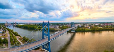 Toledo, Ohio 'daki Maumee Nehri' ni kaplayan çarpıcı mavi Anthony Wayne Köprüsü 'nün altın saat hava görüntüsü. Bu manzara kentsel gelişim ve dingin doğa arasındaki uyumu yakalar..