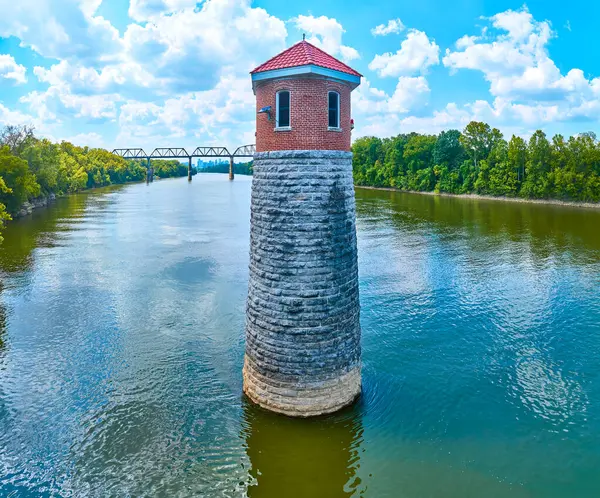 stock image Aerial view of Omohundro Waterworks Light lighthouse in Nashville. This historic stone tower stands amidst a serene river, flanked by lush trees with a steel bridge in the background under a clear