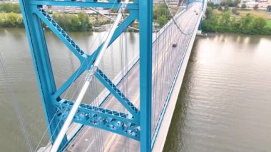Tilt Shot: Maumee Nehri üzerindeki Toledo Anthony Wayne Köprüsü 'nün hava görüntüsü, sakin mavi saat boyunca mavi ihtişamını ve kentsel zeminini sergiliyor, bağlantılar ve şehir manzarası güzelliğini ön plana çıkarıyor.