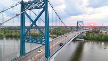 Pedestal Shot: Toledo 'daki görkemli Anthony Wayne Köprüsü' nü, şehrin doğayla buluştuğu altın saat boyunca tecrübe edin. Mimari dehayı ve sükuneti vurgulayan huzurlu bir nehir manzarası.