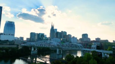 Nashvilles şehir merkezindeki altın parıltıyı yaşayın ikonik John Seigenthaler Yayaları Köprüsü 'nün canlı şehrin ufuk çizgisine karşı kurulmuş sakin Cumberland Nehri boyunca uzanması.