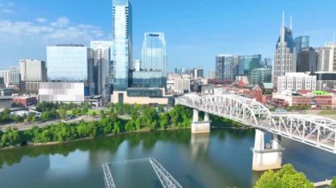 Aerial Pedestal Shot: Simgesel John Seigenthaler Köprüsü ve Cumberland Nehri üzerindeki modern ufuk çizgisi ile Nashvilles 'i keşfetmek kentsel büyümeyi ve