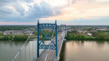 Toledo Anthony Wayne Köprüsü üzerinde çekilen hava yayı, sakin nehir ve yemyeşil nehir üzerinde güneş batarken şehrin zarafetiyle doğal güzelliği birleştirerek altın saatin dingin güzelliğini yakalar.