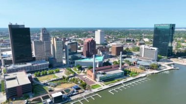 Ark Shot: Toledo şehir merkezinin canlılığını, ikonik Fifth Bank binası, ProMedica genel merkezi ve berrak mavi gökyüzüne karşı sakin Maumee Nehri 'ni gösteren hava manzarası ile tecrübe edin..
