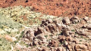 Nevada Red Rock Kanyonu 'nun havadan çekilmiş yayaları parlak güneş ışığı altında canlı kumtaşı oluşumlarını yakalar. Las Vegas yakınlarındaki engebeli güzelliği ve engin çöl manzarasını tecrübe edin. Yolculuk için mükemmel.