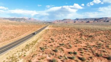 Utah, Kasırga 'daki Gooseberry Mesa' nın dingin güzelliğini görün. Beyaz bir araç uçsuz bucaksız çöl arazisinde geziyor, serüvenleri kumların ve açık mavi gökyüzünün arasına davet ediyor..