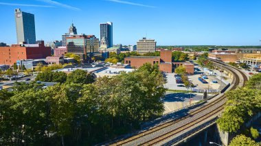 Fort Wayne Indiana 'nın havadan görünüşü tarihi ve modern mimariyi harmanlayan canlı bir şehir manzarası yakalar. Tren rayları ve yemyeşil yeşil açık mavi altında kentsel planlamayı ve bağlantıyı vurguluyor