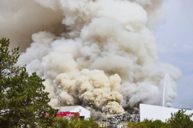 İtfaiyeciler hurda metal yangınını kontrol etmek için çalışırken Columbus Oto Parçalama 'dan yoğun duman bulutu yükseliyor. Gündüz endüstriyel yangın Ohio 'daki acil durum tepkisini vurguluyor.