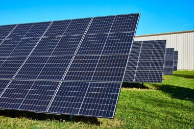 Sunlit solar panels stretch across a vibrant field in Waterloo Indiana showcasing sustainable technology in a rural setting. Perfect for highlighting green energy and renewable resource themes. clipart