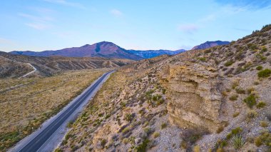 Uçsuz bucaksız çölün içinden geçen dolambaçlı bir yolu olan Nevada, Charleston Dağı 'nın görkemli hava manzarası. Gün doğumu gökyüzünü yumuşak renklerle boyar, yalnızlığın, maceranın ve doğal güzelliğin özünü yakalar..
