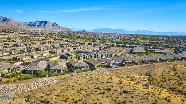 Mountain Springs Nevada 'nın havadan görünüşü modern yaşam ve çöl güzelliğinin karışımını vurgulayan Kızıl Kaya Kanyonu' nun dramatik zeminine karşı genişleyen bir banliyö mahallesini gözler önüne seriyor..