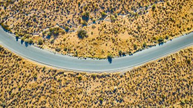 Nevada 'daki Red Rock Kanyonu' nun kurak arazisinden geçen dolambaçlı bir yolun havadan görünüşü. Pürüzsüz kıvrımlar engebeli çöl arazisiyle tezat oluşturuyor. Macera ve keşif temaları için mükemmel..
