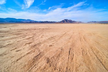 Boulder City Nevada yakınlarındaki engin çöl manzarasında açık mavi gökyüzünün altında çatlamış toprak ve engebeli dağlar var. Amerika 'nın güneybatısında yalnızlık dayanıklılık ve doğal güzellik temaları için mükemmel..