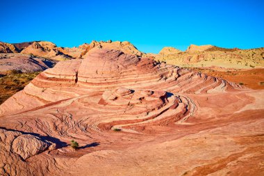 Ateş Vadisi Parkı 'ndaki Ateş Dalgası oluşumunda kırmızı ve turuncu kıvrımların canlı renkleri. Nevada Moapa Vadisi 'ndeki bu çarpıcı çöl manzarası, açık mavi gökyüzünün altında maceraya ve dehşete davetiye çıkarıyor..