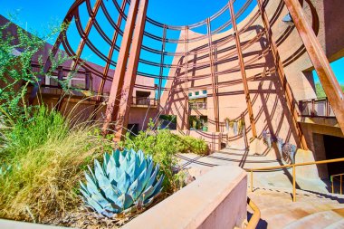 Modern desert architecture in harmony with nature at a Las Vegas Botanical Conservatory. Rust-colored framework contrasts with vibrant succulents under a clear blue sky, showcasing sustainable design. clipart