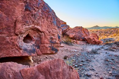 Nevada, Moapa Vadisi 'nin engebeli güzelliğini yaşayın. Bu büyüleyici Ateş Vadisi ikonik kırmızı kaya oluşumlarıyla, engin mavi gökyüzünün altında altın saat ışığı altında yıkanmış..