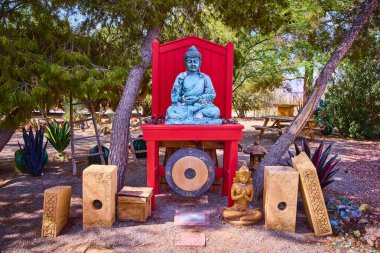 Huzurlu bir meditasyon bahçesi, Mount Charleston, Nevada 'da, kırmızı bir platformun üzerinde huzurlu bir Buda heykeli, yemyeşil ve büyük bir gong ile çevrili, ruhani inzivaya çekilme ve sessizlik için mükemmel