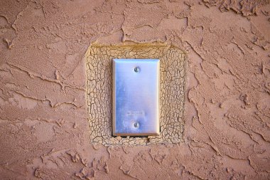 A sleek metallic switch plate contrasts with a rustic stucco wall, capturing the essence of modernity and tradition at a Las Vegas conservatory. Perfect for architecture or interior design projects. clipart