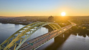 Cincinnati 'deki Daniel Carter Sakal Köprüsü' nün üzerinde gün doğumu Ohio Nehri üzerinde altın bir parıltı yayıyor. Köprü ve şehir silüeti nefes kesici bir şehir güzelliği ve bağlantı manzarası yaratıyor..