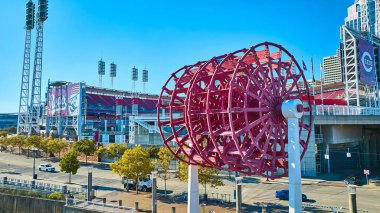 Vibrant scene at Cincinnati Great American Ball Park, showcasing the iconic red paddle wheel sculpture against a sunny backdrop. Capture the energy of Ohios rich sports and river history. clipart