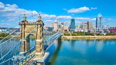 Ohio Nehri 'ni kaplayan tarihi John A Roebling Askı Köprüsü' nün havadan görünüşü ve Cincinnati modern silueti arka plan olarak kullanılıyor. Güneşli bir günde tarihin ve kentsel gelişimin mükemmel bir karışımı..