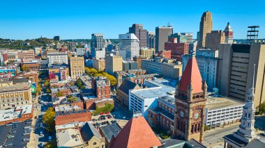 Cincinnati, Ohio şehir merkezinin havadan görünüşü: Gökdelenler ve tarihi cazibenin bir karışımı. Berrak mavi gökyüzünün altında canlı bir siluete karşı ikonik kırmızı çatılı saat kulesi. Şehir hayatı en iyi haliyle.