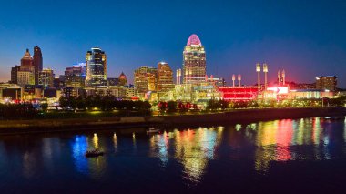 Cincinnati 'nin mavi saatindeki göz kamaştırıcı hava manzarası, Ohio Nehri' nin şehir ışıklarını yansıttığı canlı ufuk çizgisini gösteriyor. Şehir enerjisi ve mimari güzellik temaları için mükemmel..
