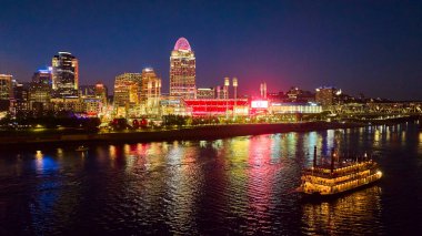 Klasik bir nehir teknesi nostaljik bir dokunuş ekledikçe Cincinnati 'nin hareketli silueti Ohio Nehri üzerinde parlıyor. Büyük Amerikan Top Parkı parlıyor, şehrin enerjik gece hayatını ve şehir cazibesini yakalıyor..